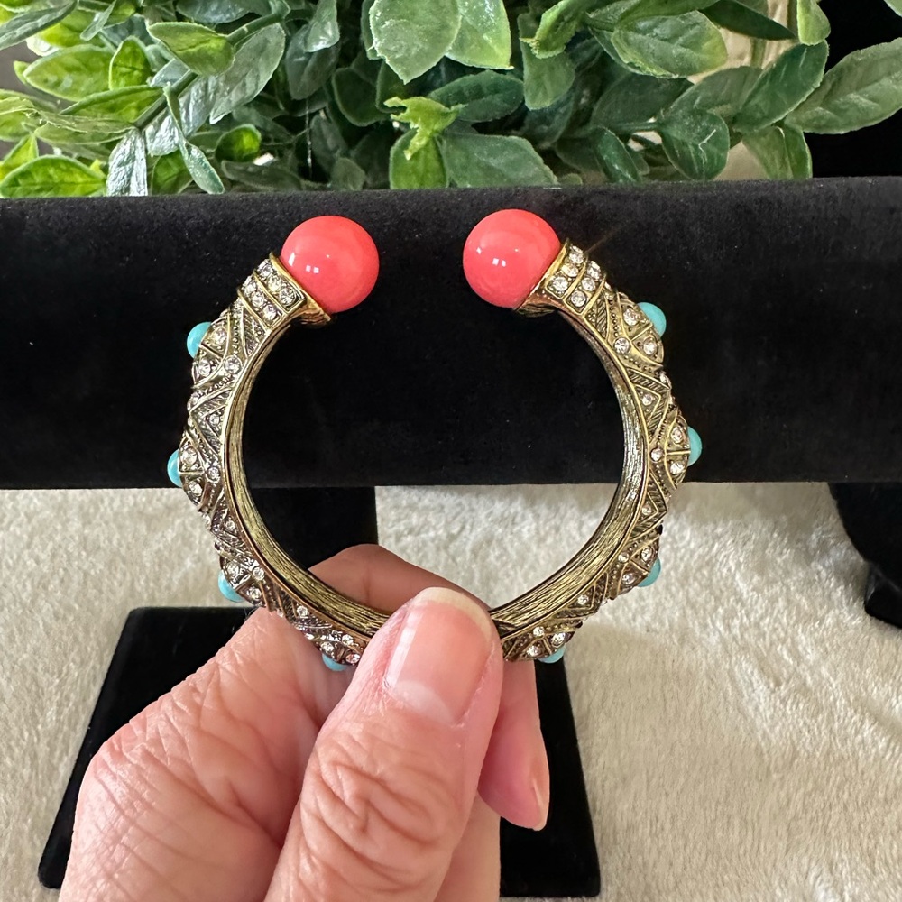 Heidi Daus Coral and Turquoise Hinged Bangle on a Gold toned Backdrop